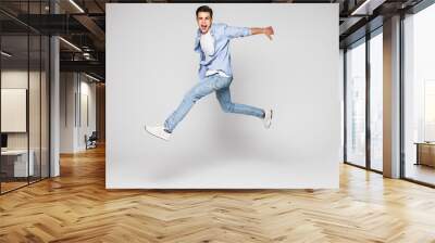 Handsome young man jumping isolated on white background Wall mural